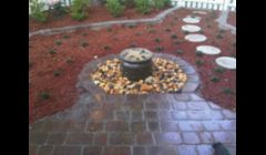 Bubbling water feature with paver patio and border surrounding it.