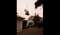 Craning a mini excavator of Judge Stirling's house for back yard up grades.