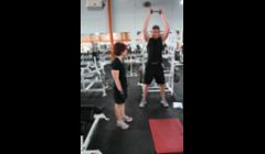 Demonstrating a squat to a front wood-chop and lift exercise. This is a total body exercise that engages legs, core, back, and shoulders.