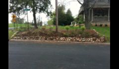 Small boulder retaining wall along street to prevent erosion and mulch from washing away